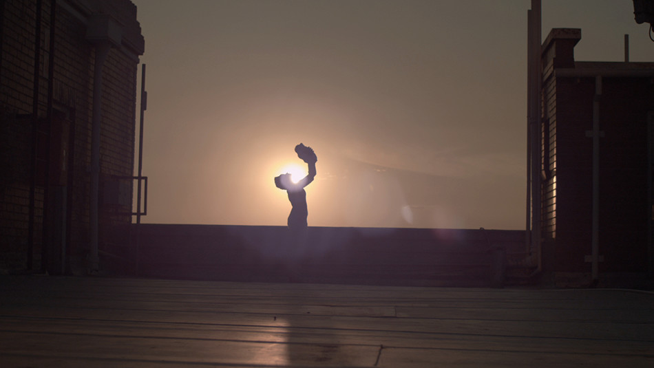 A woman holding her baby up with sun behind her